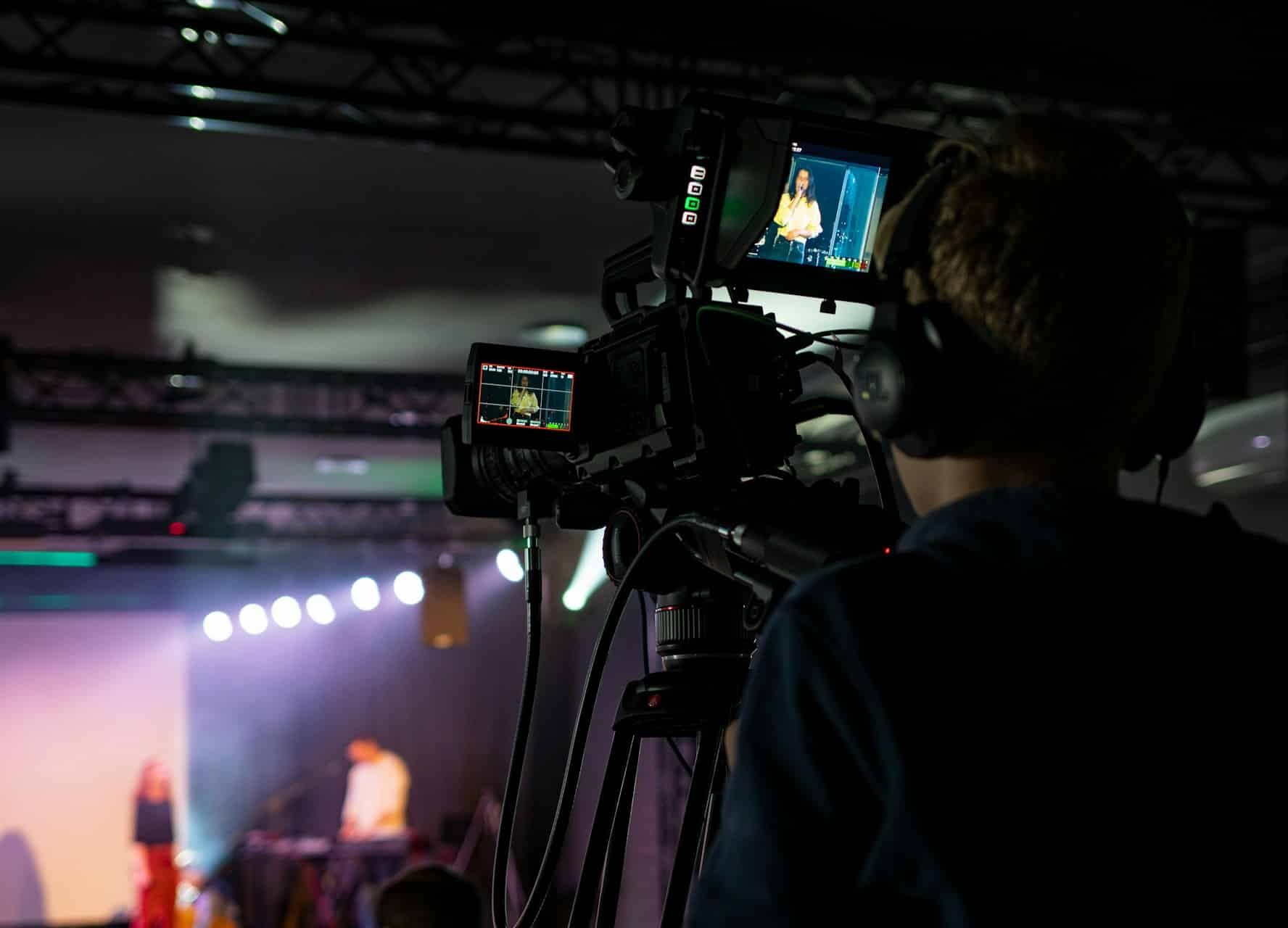 Film crew working on event coverage with cameras and tripods.